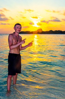 Yakışıklı erkek turist tropik cennet adası Kuramathi 'de lüks bir tatil için. Palmiye ağaçları, beyaz kum turkuaz sular ve Rasdhoo Atoll Maldivleri' nde muhteşem altın renkli günbatımı..