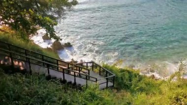 Tahta merdivenler ve kumsala giden patika turkuaz mavi su kayalıkları kayalar güneş kayaları palmiye ağaçları ve Playa Carrizalillo Meksika 'da büyük sörfçü dalgaları..