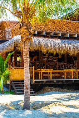 Puerto Escondido Oaxaca Meksika 13. Kasım 2022 Şemsiyeler Şemsiyeler güneşlenirken insanlar Zicatela Puerto Escondido Oaxaca Meksika 'daki tropikal Meksika plajlarında restoranlar ve dalgalar açıyorlar..