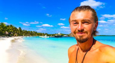 Yakışıklı erkek turist erkek gezgin muhteşem manzara manzarası turkuvaz mavi palmiye ağaçları mavi gökyüzü tropikal plaj ve ormanlar güzel Meksika adası Contoy.