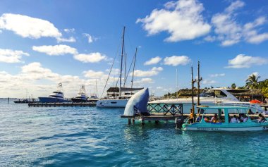 Cancun Quintana Roo Meksika 24. Mart 2022 Tekne Sürat Tekneleri Yatları ve Jetty iskelesi ve Cancun Quintana Roo Mexico 'daki Isla Mujeres adasında mavi turkuaz su ve denizde turistler.