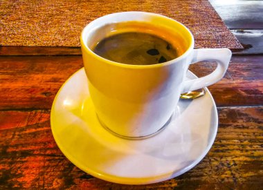 Playa del Carmen Quintana Roo Meksika 'daki restoran kafeteryasında bir tabak kaşık ve tabakla bir bardak koyu americano kahvesi..