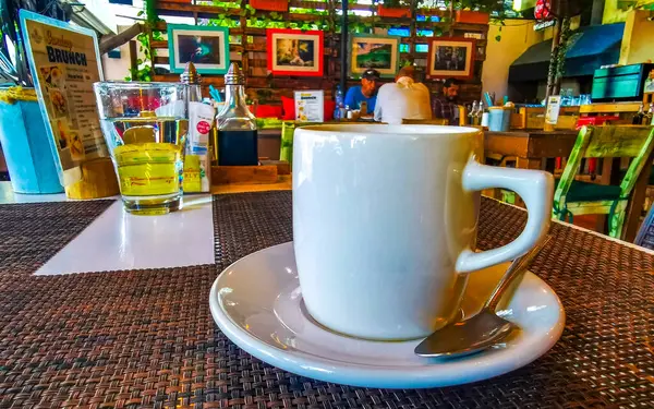 Playa del Carmen Quintana Roo Meksika 'daki restoran kafeteryasında bir tabak kaşık ve tabakla bir bardak koyu americano kahvesi..