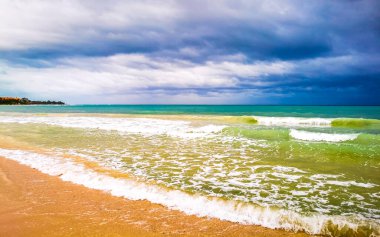 Playa del Carmen Meksika 'da berrak turkuvaz mavi su dalgaları ve kara bulutlarla şaşırtıcı tropikal Meksika Karayip plajı ve deniz manzarası manzarası..