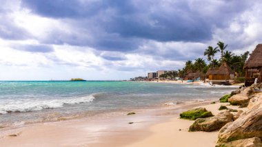 Tropik Meksika Karayip plajı ve denizi kulübeleriyle kulübeleriyle çatı palapa güneşiyle güneşleniyor güneş şemsiyeleriyle turkuaz su otelleri Playa del Carmen Meksika 'da tatil yapıyor..