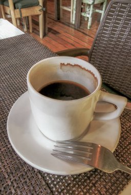 Playa del Carmen Quintana Roo Meksika 'daki restoran kafeteryasında bir tabak kaşık ve tabakla bir bardak koyu americano kahvesi..