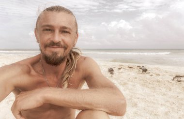 Uzun saçlı erkek turist, Playa del Carmen Quintana Roo Meksika 'daki Meksika Karayip plajında selfie fotoğraf modeline poz veriyor..
