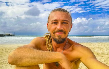 Uzun saçlı erkek turist, Playa del Carmen Quintana Roo Meksika 'daki Meksika Karayip plajında selfie fotoğraf modeline poz veriyor..