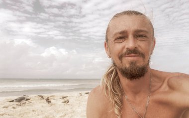 Uzun saçlı erkek turist, Playa del Carmen Quintana Roo Meksika 'daki Meksika Karayip plajında selfie fotoğraf modeline poz veriyor..