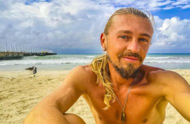 Uzun saçlı erkek turist, Playa del Carmen Quintana Roo Meksika 'daki Meksika Karayip plajında selfie fotoğraf modeline poz veriyor..
