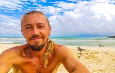 Uzun saçlı erkek turist, Playa del Carmen Quintana Roo Meksika 'daki Meksika Karayip plajında selfie fotoğraf modeline poz veriyor..