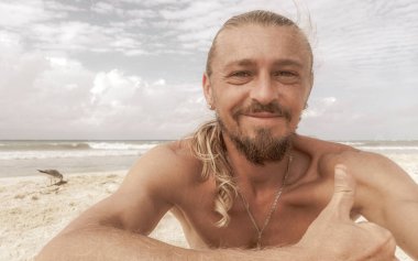 Uzun saçlı erkek turist, Playa del Carmen Quintana Roo Meksika 'daki Meksika Karayip plajında selfie fotoğraf modeline poz veriyor..