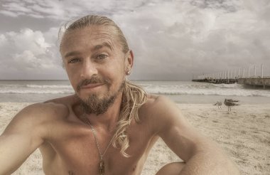 Uzun saçlı erkek turist, Playa del Carmen Quintana Roo Meksika 'daki Meksika Karayip plajında selfie fotoğraf modeline poz veriyor..