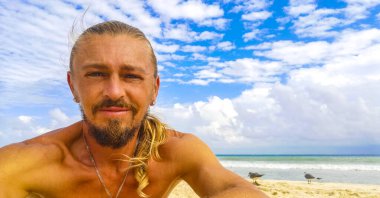 Uzun saçlı erkek turist, Playa del Carmen Quintana Roo Meksika 'daki Meksika Karayip plajında selfie fotoğraf modeline poz veriyor..