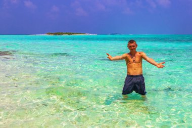 Male young sexy tourist traveler man enjoys vacation in color gradient water at the sandbank islands Madivaru and Finolhu in Rasdhoo Atoll Maldives. clipart