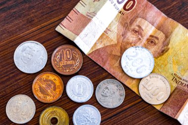 Endonezya 'daki 5000 gagalı rupia parası farklı paralarla dolu ahşap bir masada..