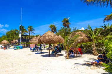 Playa del Carmen Quintana Roo Meksika 06. Temmuz 2024 Tropikal Karayip plajı ve deniz eğlenceli insanlarla güneş şemsiyeleri ve palapa sazlı çatı turkuaz suyu Playa del Carmen Meksika.