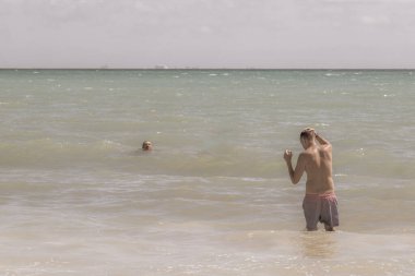 Erkek turist, fotoğraf mankeni olarak geziyor ve Playa del Carmen Quintana Roo Meksika 'daki Meksika Karayip sahillerinde yüzüyor..