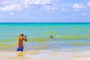 Erkek turist, fotoğraf mankeni olarak geziyor ve Playa del Carmen Quintana Roo Meksika 'daki Meksika Karayip sahillerinde yüzüyor..