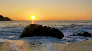 Güzel, göz kamaştırıcı, renkli ve altın sarısı günbatımı. Plajda sarı turuncu kırmızı ve büyük bir sörfçü dalgası ve kayalıklar. Zicatela Puerto Escondido Oaxaca Meksika 'da tropikal doğada uçurum manzarası..