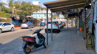 Tipik renkli turist caddesi yolu ve şehir arabalarıyla kaldırım oteller, restoranlar ve Zicatela Mexico 'daki insanlar..