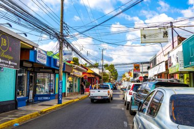 Trafik kaldırımları olan tipik cadde araba mağazaları ve Orta Amerika Alajuela Kosta Rika 'daki insanlar.