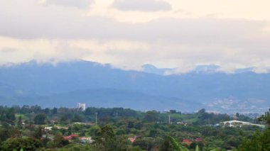 Orman ağaçları, bulutlar ve Orta Amerika 'daki San Jos ve Heredia Kosta Rika' nın doğasıyla güzel bir dağ manzarası ve şehir manzarası..