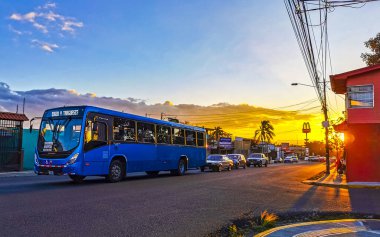 Gündoğumu günbatımında tipik caddelerde trafik kaldırımları araba mağazaları ve Orta Amerika Alajuela Kosta Rika 'daki insanlar.