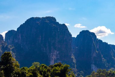 Güneydoğu Asya 'daki Vang Vieng Vientiane Eyaleti Laos' ta tropikal orman tepeleri kayalar ve mavi gökyüzü ile dağ zirvesi..