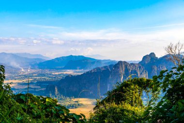 Güneydoğu Asya 'daki Vang Vieng Vientiane Eyaleti Laos' ta tropikal orman tepeleri kayalar ve mavi gökyüzü ile dağ zirvesi..