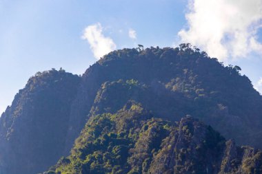 Güneydoğu Asya 'daki Vang Vieng Vientiane Eyaleti Laos' ta tropikal orman tepeleri kayalar ve mavi gökyüzü ile dağ zirvesi..