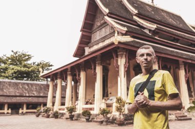 Male tourist man at Wat Si Saket buddhist buddha temple in Vientiane Laos in Southeastasia Asia. clipart