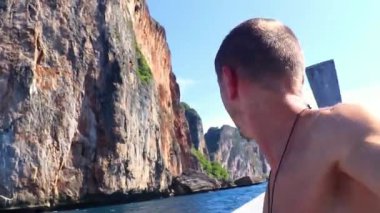 Turist erkek adam güzel kireçtaşı kayalıklarında ve turkuaz mavi sularda fotoğraf çekiyor Koh Phi Phi Leh adası Ao Nang Krabi Tayland.