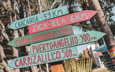 Zicatela Puerto Escondido Oaxaca Meksika 'daki plajlara ve yerlere renkli yön işaretleri.