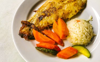 Meksika 'da Akumal Quintana Roo' da pirinç ve sebzelerle servis edilen sarımsaklı balık..