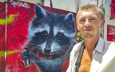 Male russian tourist traveler at typical street road and cityscape tourism with racoon raccoon graffiti painting of Playa del Carmen in Quintana Roo Mexico. clipart