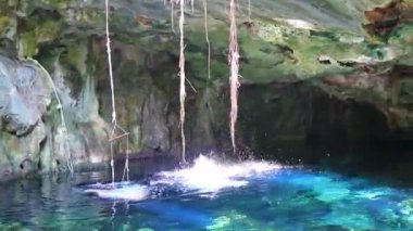 Erkek tur rehberi, Xpu Ha Quintana Roo Mexico 'daki bir kireçtaşı mağarasından turkuaz yeşil suya atlıyor..