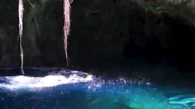 Erkek tur rehberi, Xpu Ha Quintana Roo Mexico 'daki bir kireçtaşı mağarasından turkuaz yeşil suya atlıyor..