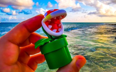 Carnivorous plant super mario figure in the hand on the beach in Playa del Carmen Quintana Roo Mexico. clipart