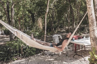 Erkek turist tropikal ormanda ve doğada dinleniyor. Kireçtaşı kayaları, palmiye ağaçları ve Xpu Ha Quintana Roo Mexico 'daki Cenote Park Minotauro bitkileriyle..