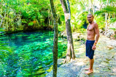 Erkek turist erkek tropikal ormanı ve doğası kireçtaşı palmiye ağaçları, kayalar turkuaz mavi su Xpu Ha Quintana Roo Mexico Cenote Park Minotauro.