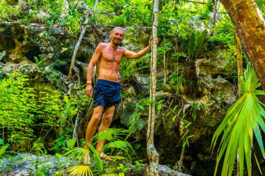 Erkek turist erkek tropikal ormanı ve doğası kireçtaşı palmiye ağaçları, kayalar turkuaz mavi su Xpu Ha Quintana Roo Mexico Cenote Park Minotauro.