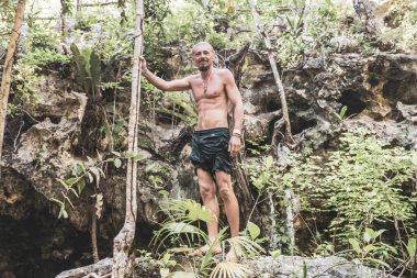 Erkek turist erkek tropikal ormanı ve doğası kireçtaşı palmiye ağaçları, kayalar turkuaz mavi su Xpu Ha Quintana Roo Mexico Cenote Park Minotauro.