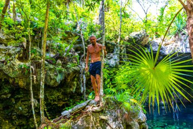 Erkek turist erkek tropikal ormanı ve doğası kireçtaşı palmiye ağaçları, kayalar turkuaz mavi su Xpu Ha Quintana Roo Mexico Cenote Park Minotauro.