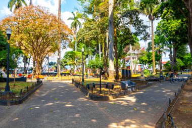 Orta Amerika Alajuela Kosta Rika 'da heykelleri ve bankları olan güzel tropikal Central Park.