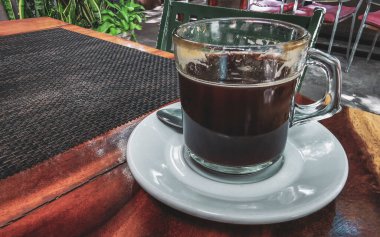 Playa del Carmen Quintana Roo Meksika 'daki restoran kafeteryasında bir tabak kaşık ve tabakla bir bardak koyu americano kahvesi..