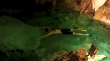 Erkek tur rehberi, Tulum Quintana Roo Mexico 'daki Yaxmulito mezarlığında turkuaz yeşil suda yüzüyor ve şnorkelle yüzüyor..