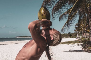 Playa del Carmen Quintana Roo Meksika sahilinde hindistan cevizi içen bir adam..