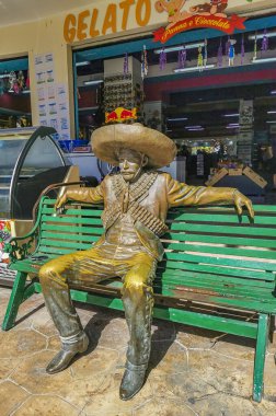 Tulum Quintana Roo Meksika 09. Mart 2022 Meksika altın madalyası Tulum Quintana Roo Meksika 'da bir bankta oturan kovboy heykeli figürü.