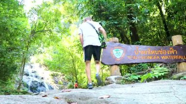 Ton Chongfa Şelalesi girişindeki erkek turist. Khao Lak Amphoe Takua Pa Phang Nga Tayland 'daki bilgi panolarına hoş geldiniz..